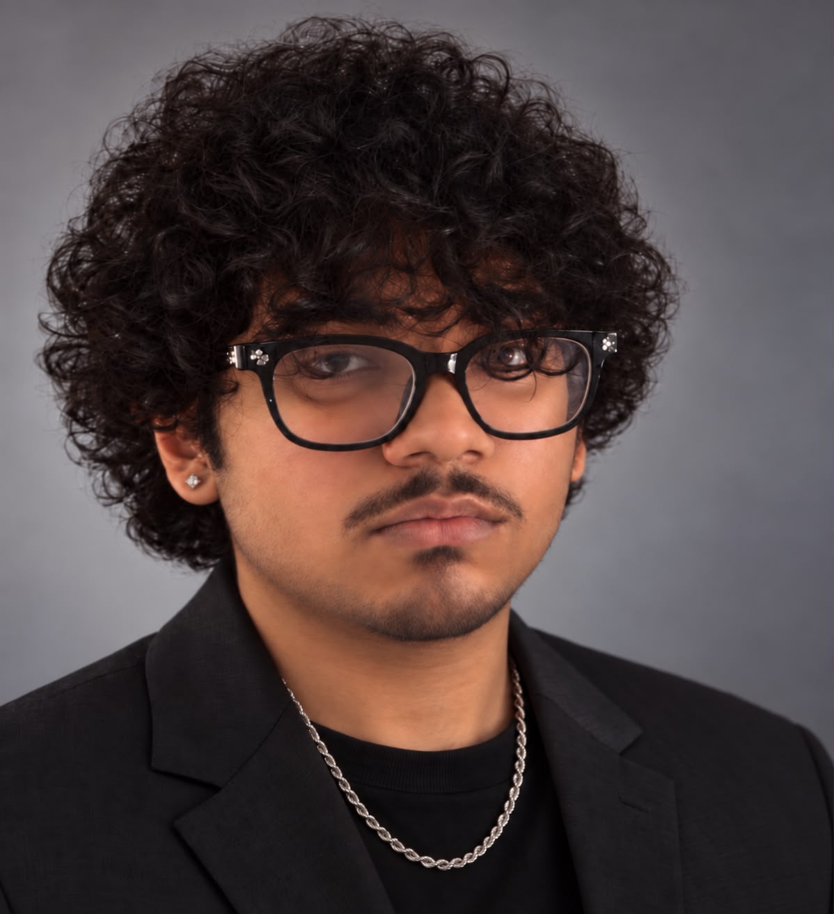 Portrait of Harshit Mishra wearing glasses and a black blazer